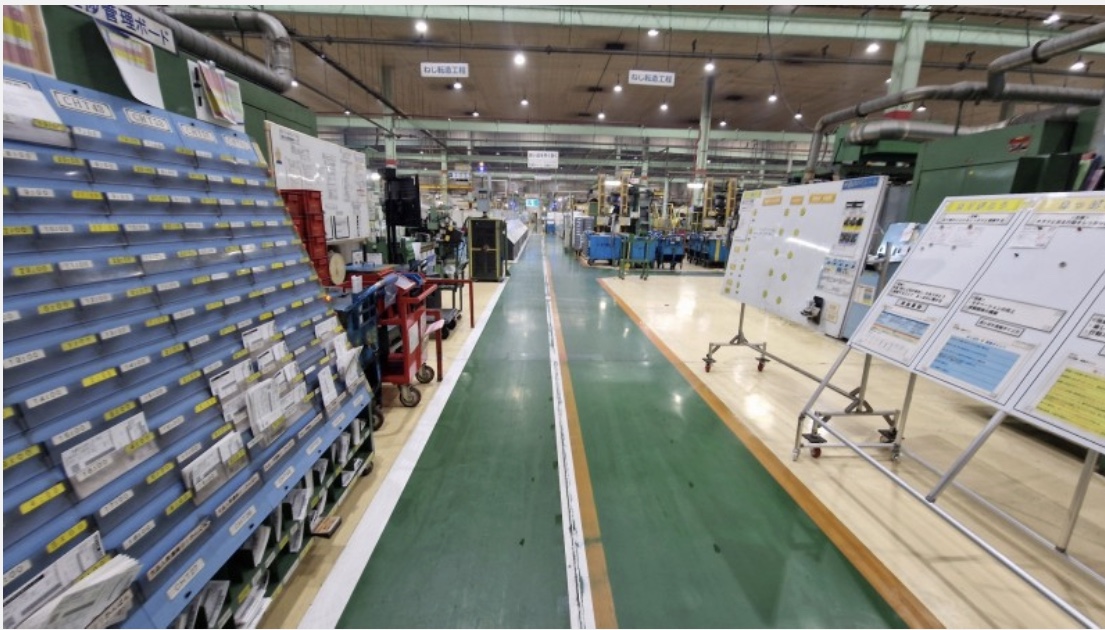 Productiehal met visueel management: materiaalkasten, prestatieborden en een gemarkeerde looproute